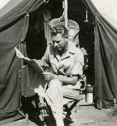 B-20.5-007-Hal Williams reading newspaper outside tent